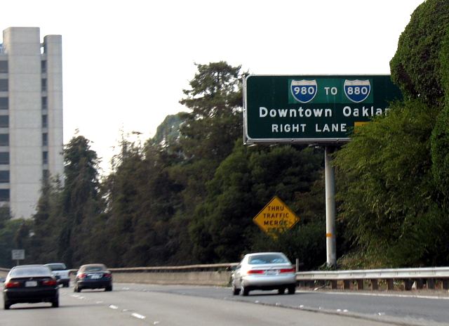 Trailblazer sign pointing the way to Interstate 880 is almost covered up by plants