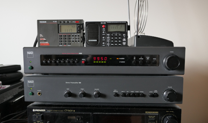 Radios compared in this part of the report: NAD 4300 AM/FM component tuner receiving KQMT(FM) Denver at 99.5 MHz, with the Qodosen DX-286 and Tecsun PL-320 sitting on top of the NAD tuner. The tuner sits on top of an NAD 106 audio preamplifier.