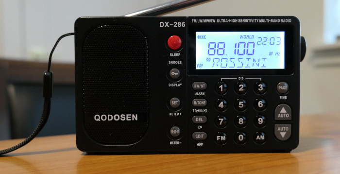 Display of Qodosen DX-286 AM/FM/SW radio showing KVOD(FM) along with the name of the artist being played (Rossini)