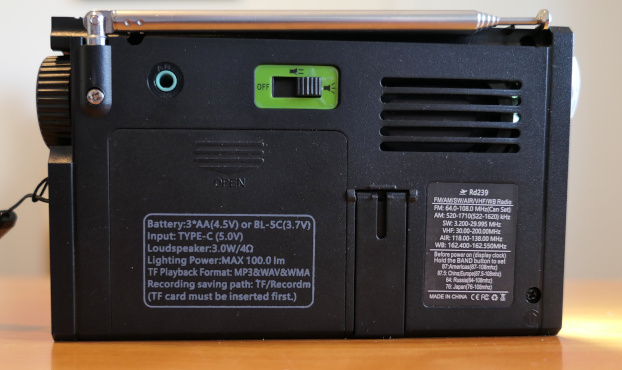 Rear of the Lijiani RD239 AM/FM/etc. radio/media player-recorder, showing the door to the battery compartement and the switch used to turn on the flashlight and the reading light. An antenna jack and the attachment for the telescoing antenna are also shown.