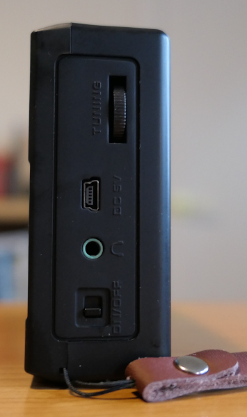 Side view of the SEMIER SM-817 radio/media player, showing a thumbwheel volume control, a USB port, an earphone jack, and an on/off switch